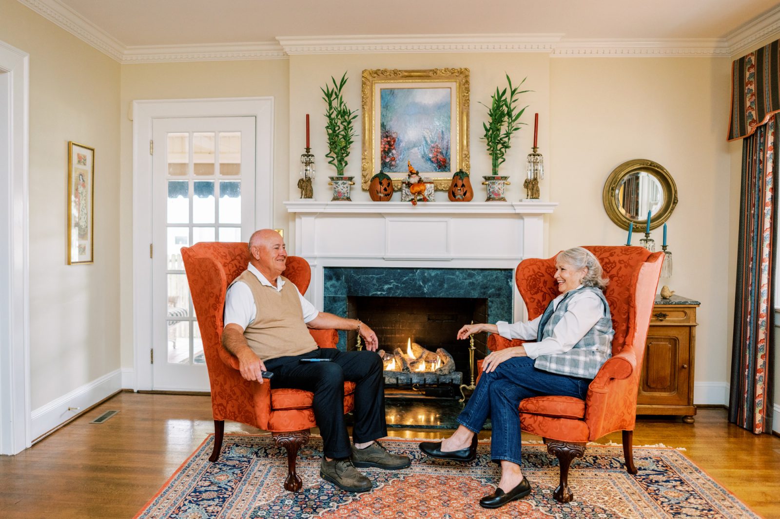 Male and female couple sitting in front of a gas fireplace.
