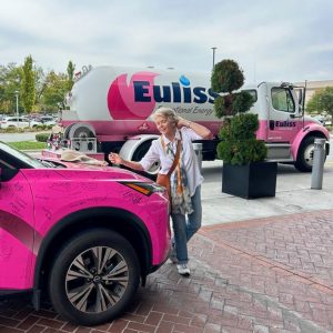 Meredith Baxter posing in front of breast cancer branded cars and propane delivery truck.