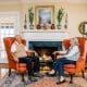 Older couple sitting on orange wingback chairs enjoying a gas fireplace to lower their energy bills.