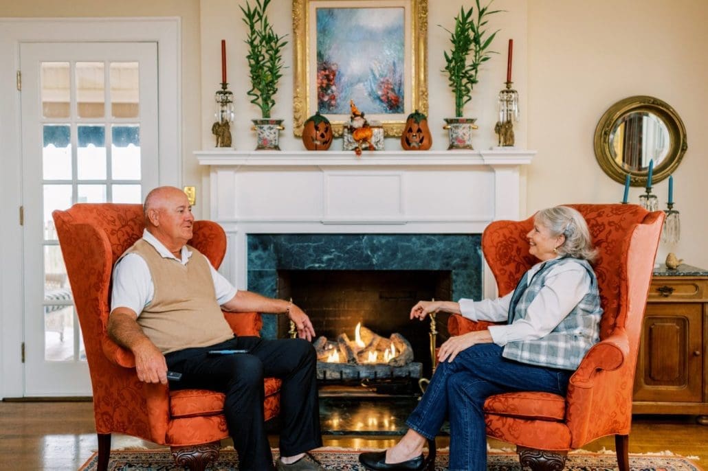 Man and woman sitting in orange armchairs in front of a gas log set in Burlington, NC.