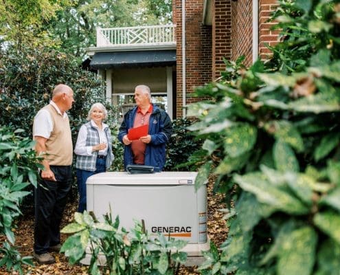 Euliss technician and two customers discussing propane generators with a Generac Generator installed.