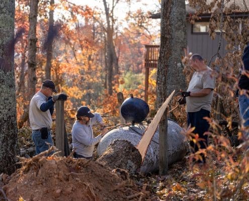 Three propane technicians work on a misplaced propane tank in Bakersville, NC after Hurricane Helene.