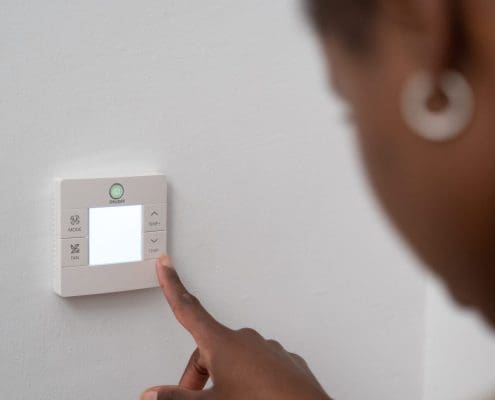 Homeowner adjusting a thermostat to lower their propane ussage.
